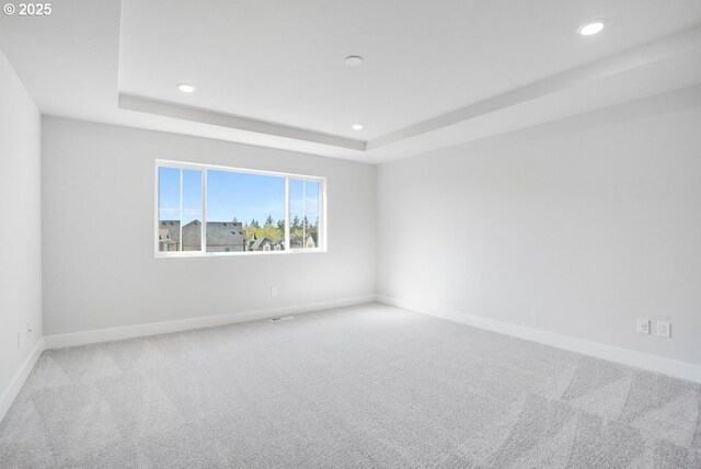 carpeted spare room featuring recessed lighting, baseboards, and a tray ceiling