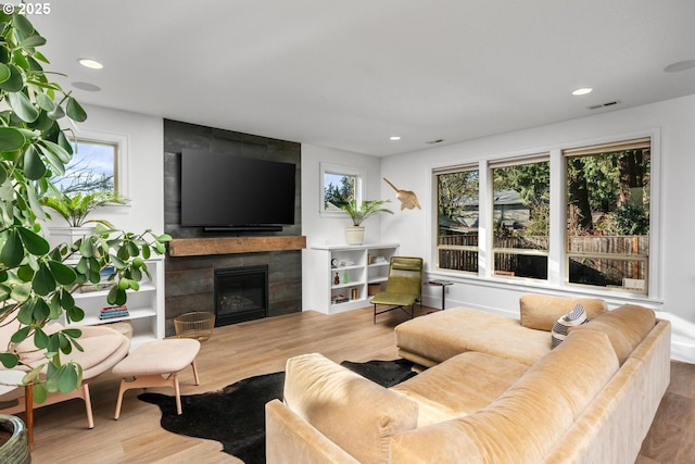 living room with a tiled fireplace and wood-type flooring