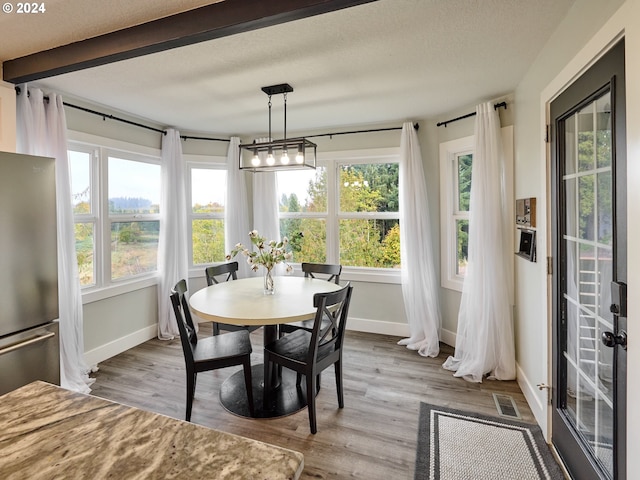 dining space with baseboards, wood finished floors, and a textured ceiling