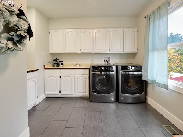 clothes washing area featuring washer and clothes dryer, baseboards, and cabinet space
