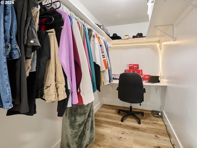 walk in closet featuring light hardwood / wood-style floors and built in desk