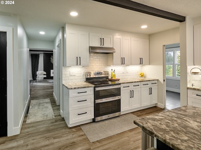 kitchen with stainless steel range with electric stovetop, white cabinetry, light stone countertops, decorative backsplash, and hardwood / wood-style floors