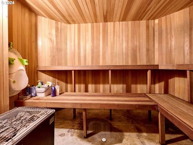 view of sauna with wooden ceiling, concrete flooring, and wooden walls