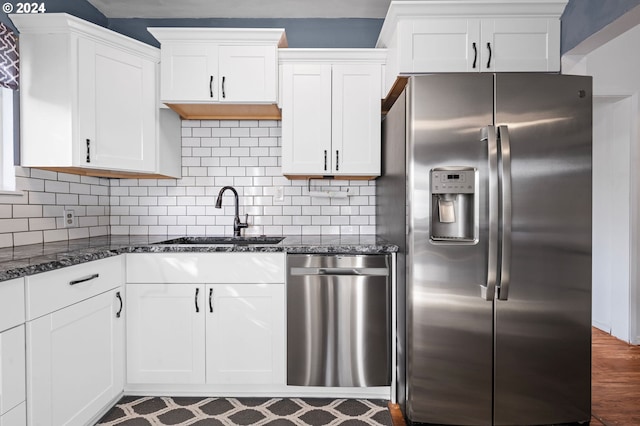 kitchen featuring sink, appliances with stainless steel finishes, white cabinetry, and dark stone counters