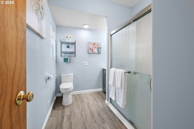 bathroom featuring vanity, a shower with shower door, hardwood / wood-style flooring, and toilet