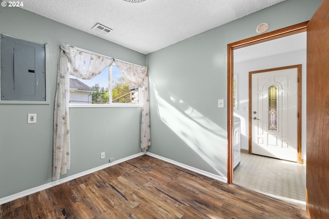 unfurnished room with hardwood / wood-style floors, electric panel, and a textured ceiling