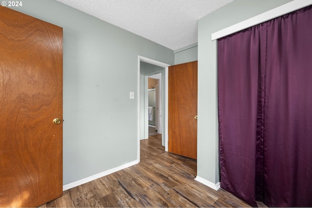 unfurnished bedroom featuring a textured ceiling and dark hardwood / wood-style flooring