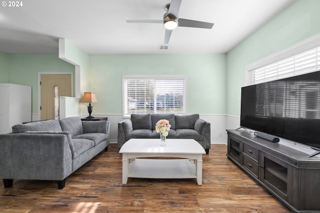 living room with dark wood-type flooring, ceiling fan, and plenty of natural light