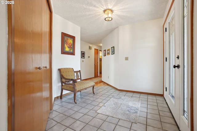foyer featuring light tile patterned floors, baseboards, and a textured ceiling