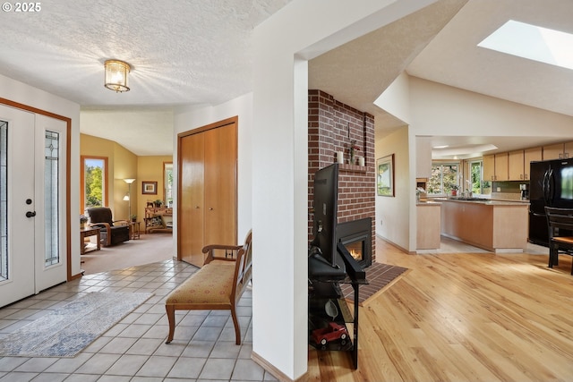 foyer with vaulted ceiling, a skylight, baseboards, and light wood-style flooring