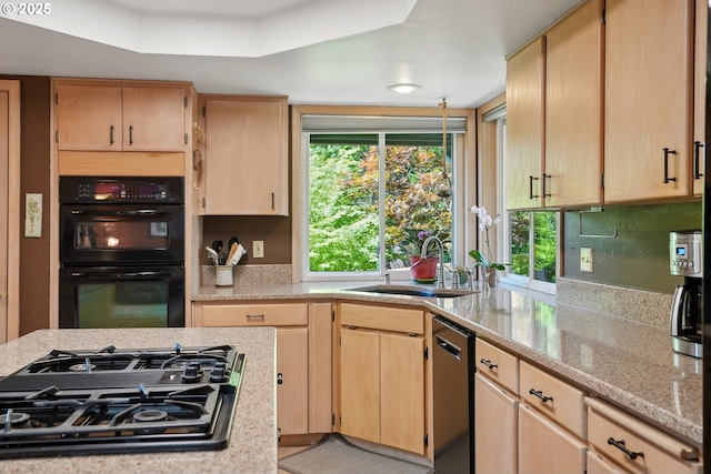 kitchen featuring black appliances, a sink, light brown cabinetry, and light stone counters