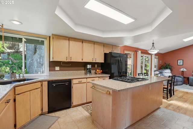 kitchen with black appliances, a tray ceiling, light brown cabinetry, and a sink