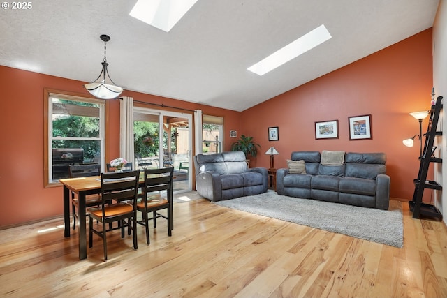 living area with a skylight, wood finished floors, and high vaulted ceiling