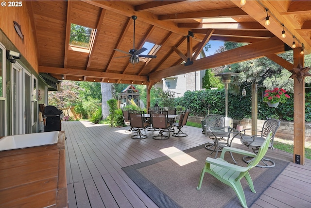 wooden deck featuring outdoor dining space, grilling area, and a ceiling fan