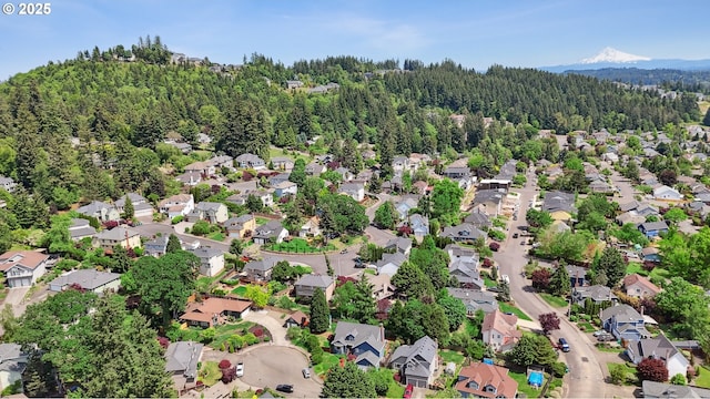 aerial view of property and surrounding area with a heavily wooded area and nearby suburban area