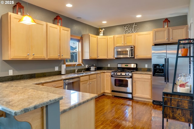 kitchen with a breakfast bar, hanging light fixtures, stainless steel appliances, light brown cabinetry, and kitchen peninsula