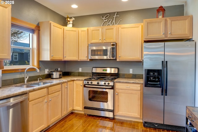 kitchen featuring stainless steel appliances, light stone countertops, sink, and light brown cabinets