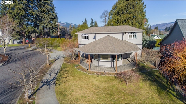 view of front of home with a mountain view, covered porch, and a front lawn