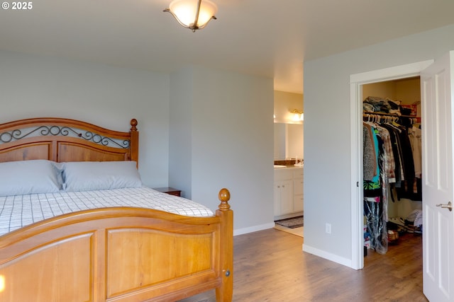 bedroom with connected bathroom, a walk in closet, hardwood / wood-style floors, and a closet