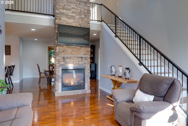 living room with a towering ceiling, a fireplace, and hardwood / wood-style floors