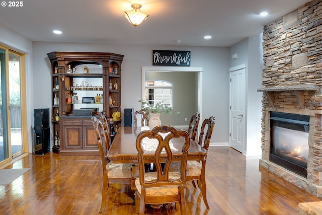 dining space with a wealth of natural light, a stone fireplace, and hardwood / wood-style floors