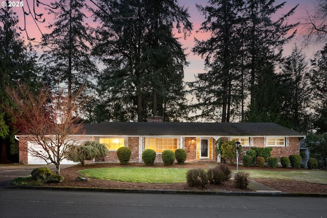 ranch-style home with driveway, brick siding, and a front yard