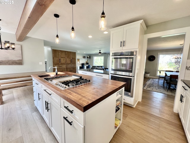 1082 E Highland Ave, Hermiston, OR 97838 - kitchen with butcher block countertops, stainless steel appliances, light wood-style floors, hanging light fixtures, and plenty of natural light