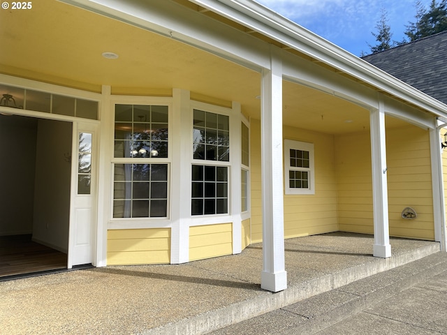 view of exterior entry with roof with shingles