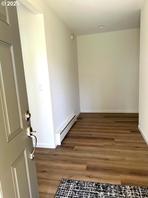 interior space featuring baseboards, baseboard heating, and wood finished floors