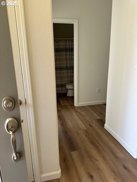 hallway featuring baseboards and wood finished floors