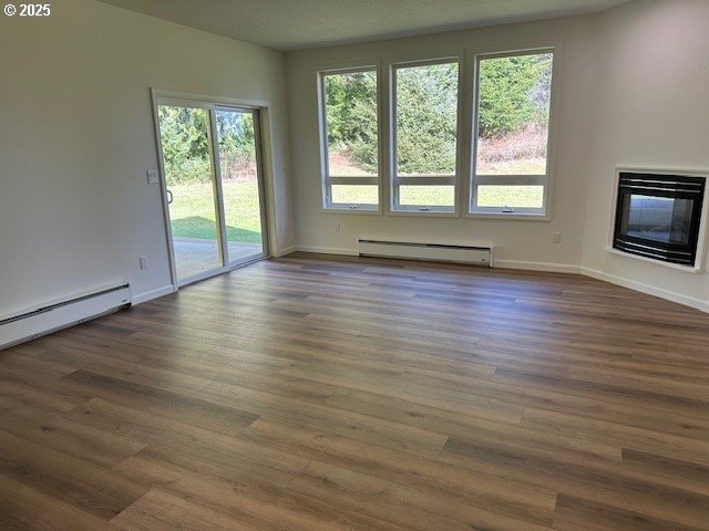 unfurnished living room featuring a baseboard heating unit, a baseboard radiator, a glass covered fireplace, and dark wood-style floors