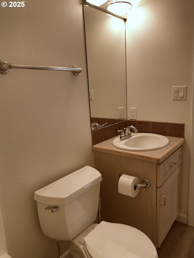 bathroom featuring a textured wall, wood finished floors, vanity, and toilet