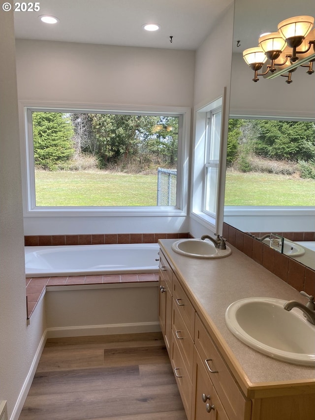 bathroom featuring recessed lighting, a sink, a bath, and wood finished floors