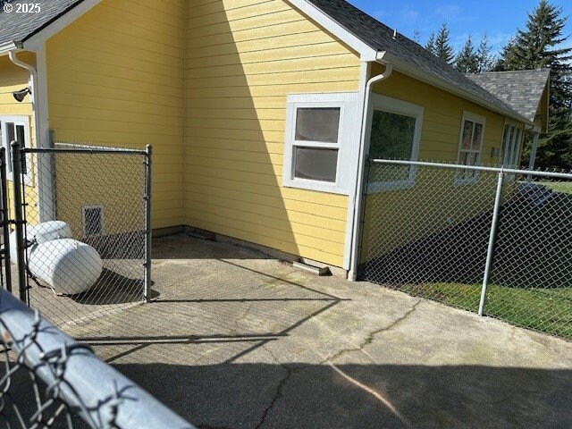 view of property exterior with a patio, a shingled roof, and fence