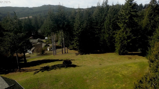 exterior space featuring a lawn, a view of trees, and a mountain view