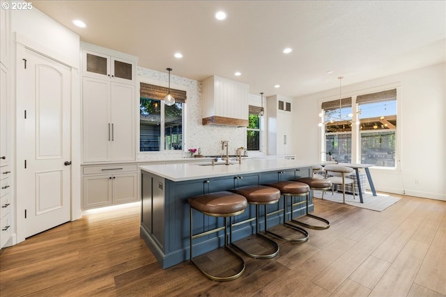 8614 SW Logan Ln, Tualatin, OR 97062 - kitchen featuring light wood finished floors, a sink, a center island with sink, white cabinetry, and recessed lighting