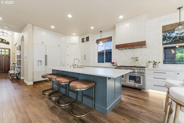8614 SW Logan Ln, Tualatin, OR 97062 - kitchen featuring high quality appliances, a sink, light countertops, arched walkways, and dark wood finished floors
