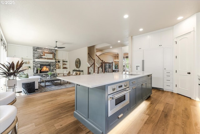 8614 SW Logan Ln, Tualatin, OR 97062 - kitchen with open floor plan, stainless steel oven, a sink, gray cabinetry, and arched walkways