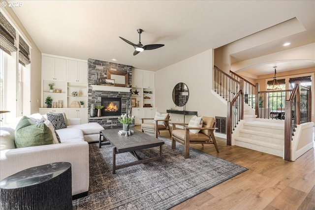 8614 SW Logan Ln, Tualatin, OR 97062 - living room with stairway, a chandelier, ceiling fan, light wood-style flooring, and a stone fireplace