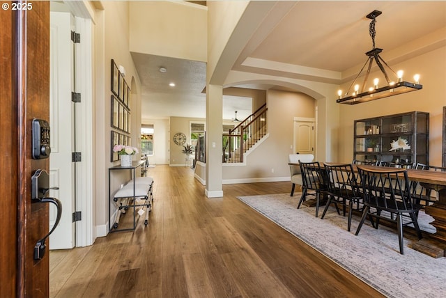 8614 SW Logan Ln, Tualatin, OR 97062 - dining space featuring arched walkways, baseboards, wood finished floors, a chandelier, and stairway