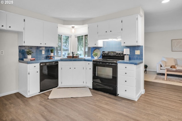 kitchen featuring white cabinetry, black appliances, under cabinet range hood, and a sink