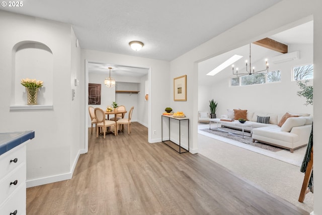 interior space featuring baseboards, vaulted ceiling with beams, light wood-type flooring, and a wall unit AC