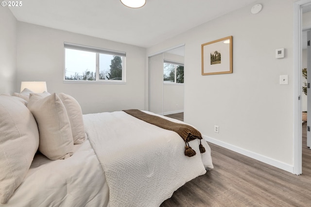 bedroom featuring wood finished floors, baseboards, and a closet