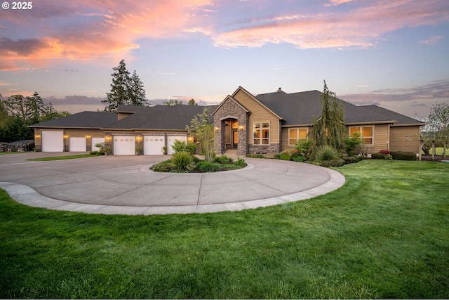 view of front of house featuring a garage, curved driveway, a yard, and stone siding