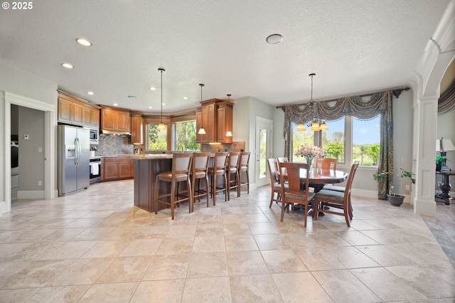 dining space featuring a notable chandelier, a textured ceiling, recessed lighting, baseboards, and light tile patterned floors