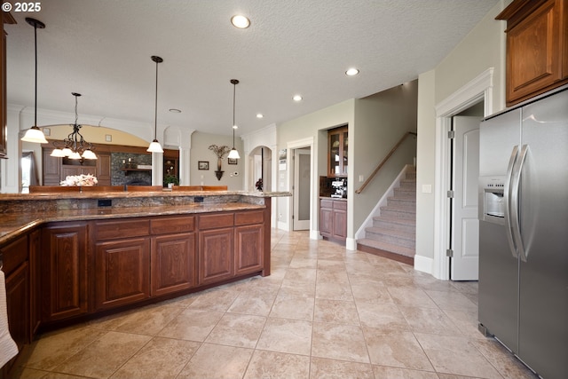 kitchen featuring pendant lighting, arched walkways, stainless steel fridge, dark stone counters, and recessed lighting