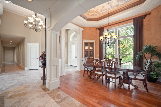 dining area with arched walkways, a chandelier, ornamental molding, and a towering ceiling