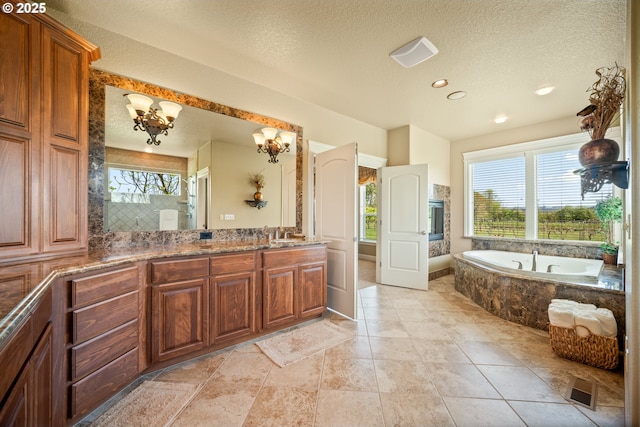 full bathroom featuring an inviting chandelier, a bath, a textured ceiling, and visible vents