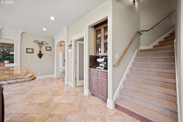 stairway featuring arched walkways, baseboards, and recessed lighting