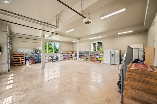 garage with stainless steel refrigerator with ice dispenser and a garage door opener